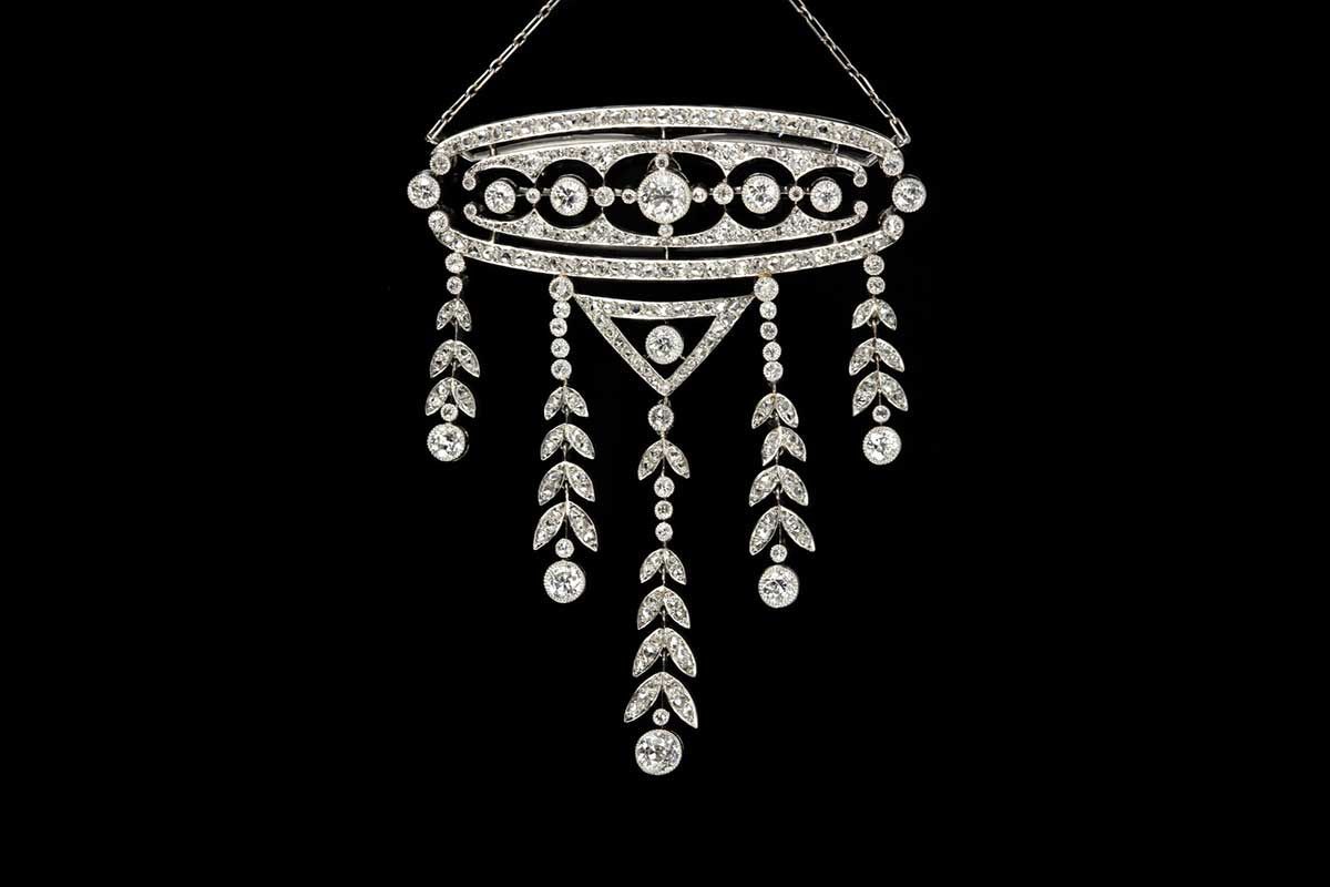 Broche ornée en argent ou en platine, sertie de diamants, présentant un motif géométrique à plusieurs niveaux sur fond noir.