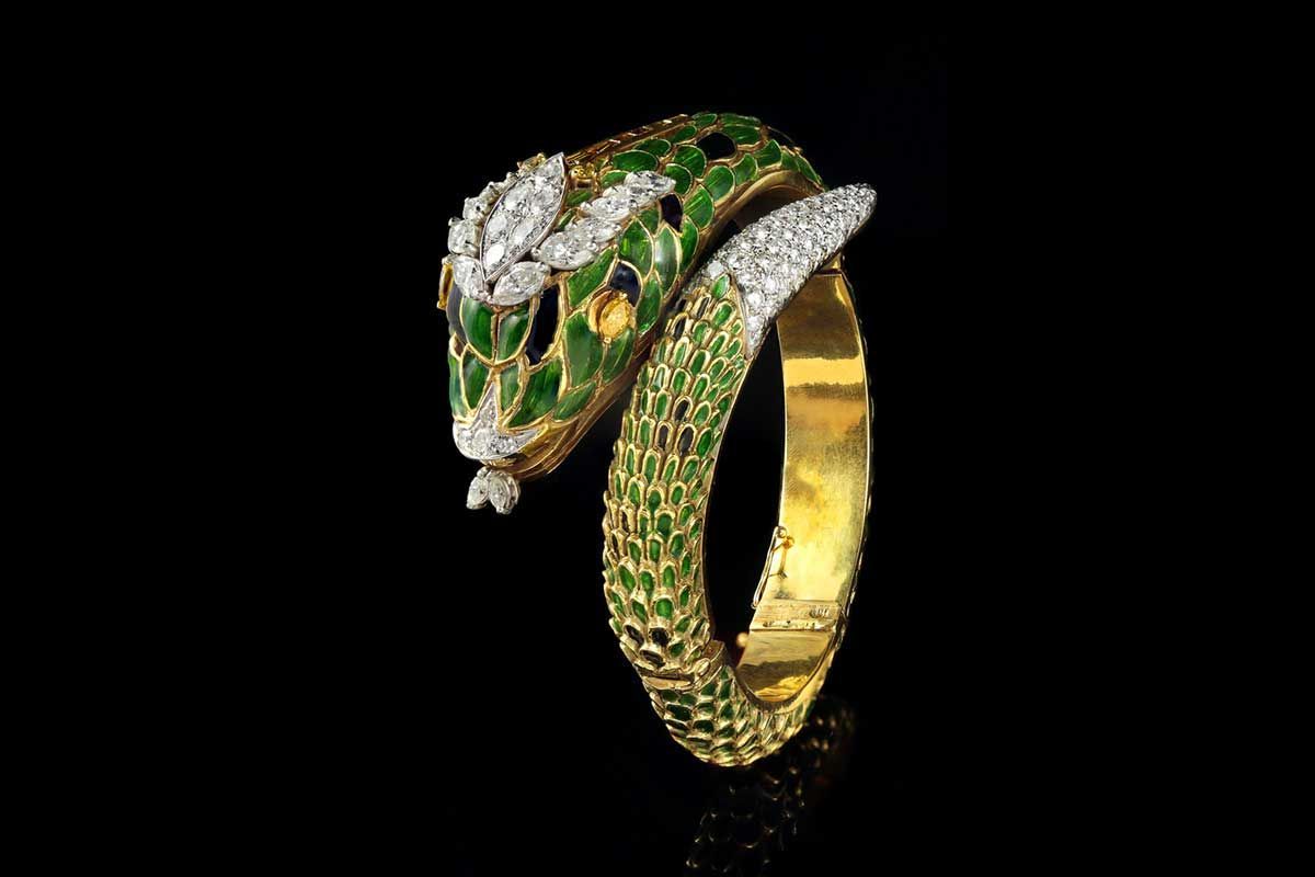 Un bracelet doré en forme de serpent orné d'écailles en émail vert, d'une tête incrustée de diamants et d'une pointe de queue également sertie de diamants.