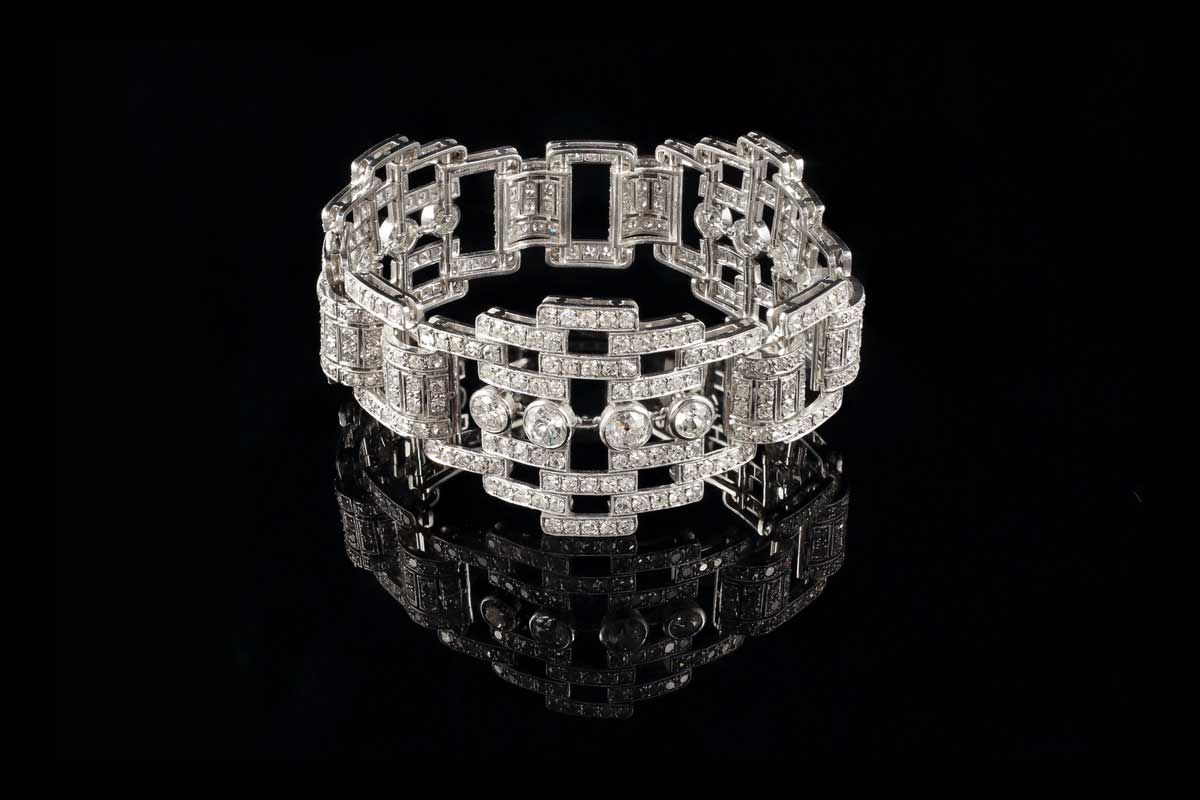 Un bracelet rectangulaire incrusté de diamants, monté sur métal blanc, se détachant sur un fond noir avec un reflet.