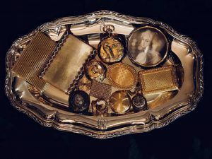 Un plateau ovale en argent présente un assortiment de montres de poche anciennes en or, leurs étuis et un portrait dans un cadre circulaire.