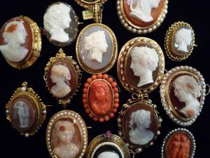 Une collection de broches camées ovales variées, ornées de profils en relief sculptés, serties dans des cadres en or sur fond noir.