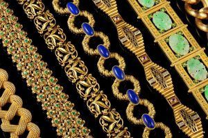 Vue de dessus de six bracelets à maillons en or différents, présentés côte à côte sur une surface noire.