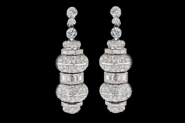 Une paire de boucles d'oreilles en diamants, de style chandelier, serties sur un fond noir uni.