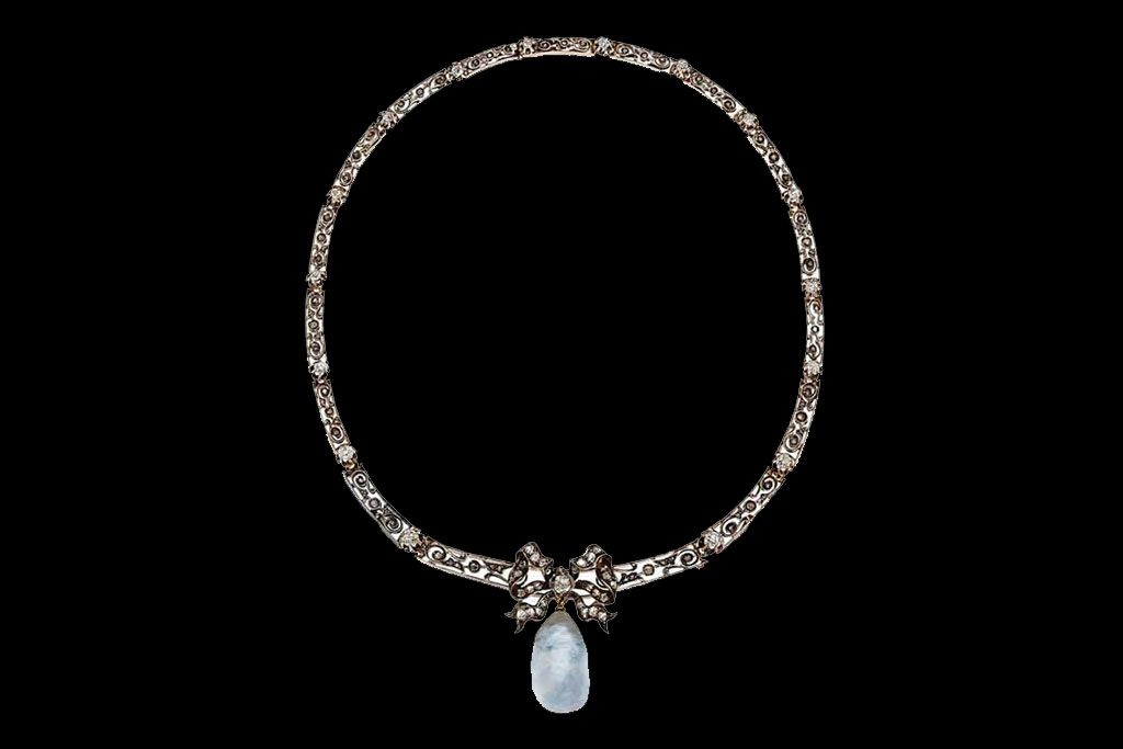 Un collier orné en métal argenté, avec un centre en forme de nœud retenant un pendentif bleu pâle en forme de poire.