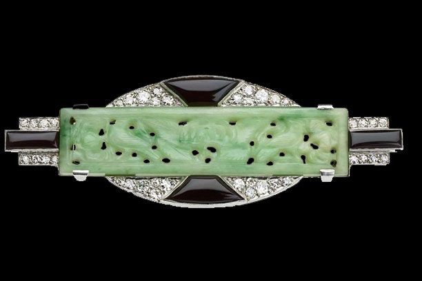 Broche Art Déco ornée d'une barre centrale sculptée en jade vert pâle, de détails en onyx noir et d'un pavé de diamants sur fond noir.