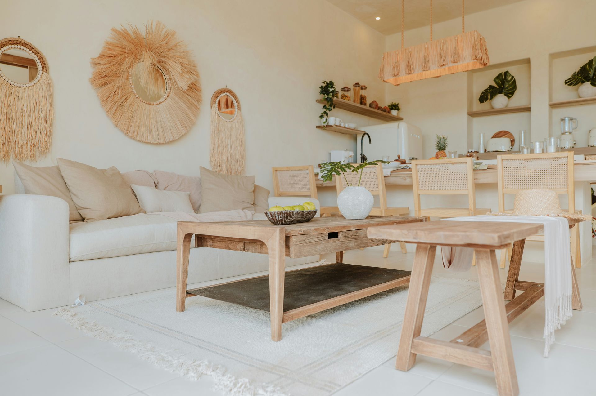Sala de estar bohemia: sofá blanco, mesa y sillas de madera, decoración de pared tejida, paleta de colores claros.