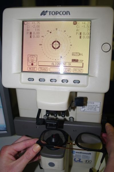 Una persona tiene un paio di occhiali davanti a un dispositivo Topcon