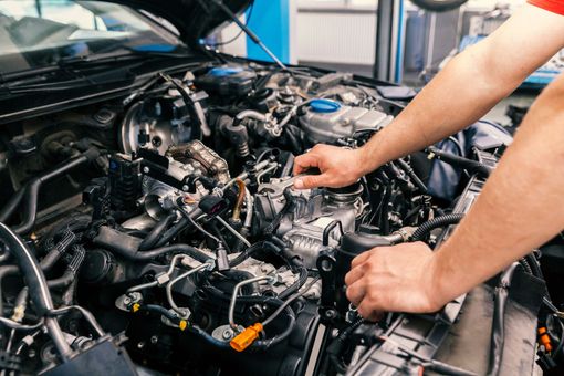 Un mécanicien travaille sur un moteur de voiture exposé dans un atelier de réparation automobile.