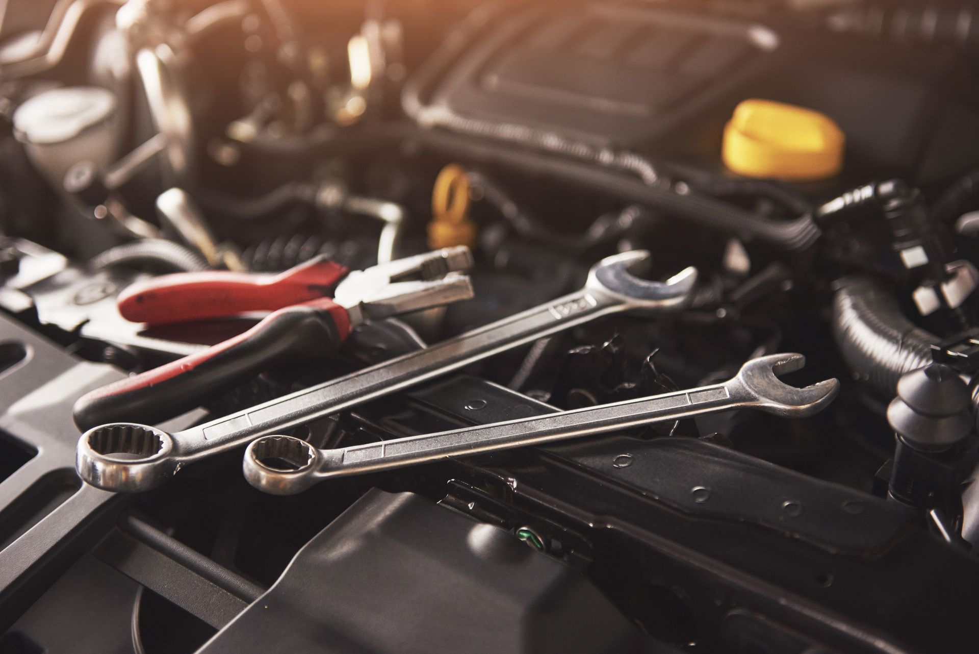 Clés et pinces diverses sur le moteur d'une voiture dans un garage faiblement éclairé
