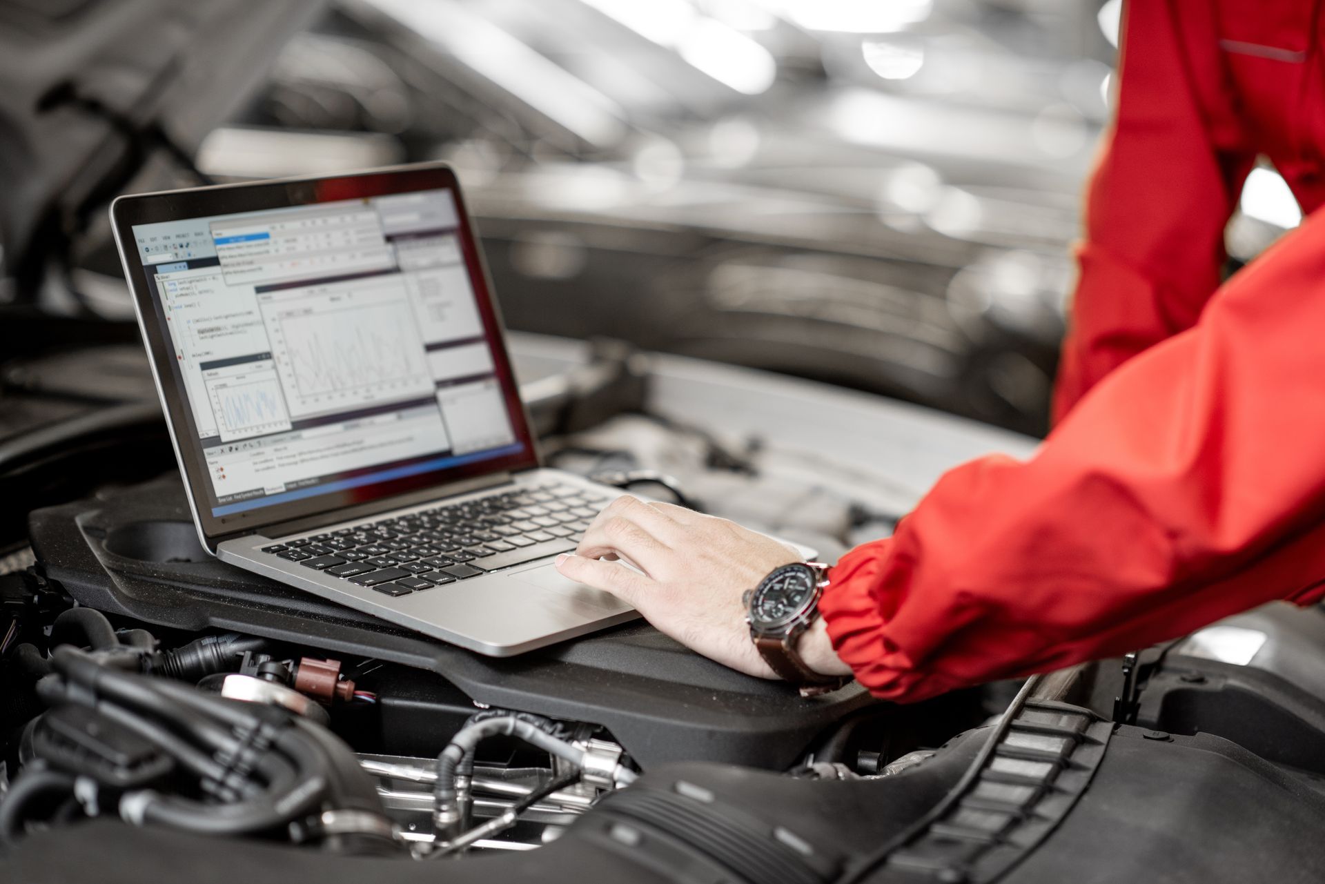 Un mécanicien utilise un ordinateur portable pour diagnostiquer un moteur de voiture dans un garage.