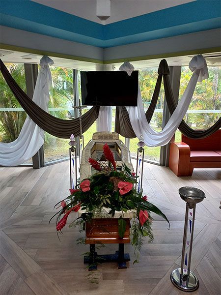 Couronne funéraire et composition florale dans une pièce lumineuse avec des drapés de tissu blanc et foncé