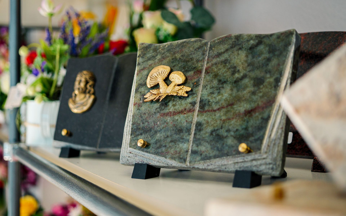 Deux plaques encadrées ornées d'emblèmes dorés sur une étagère, avec des fleurs floues en arrière-plan.
