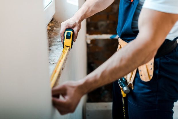 Un hombre está midiendo una pared con una cinta métrica.
