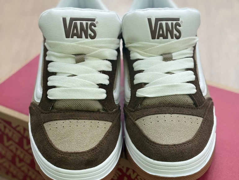 Paire de baskets Vans marron et blanches, face à l'avant, sur fond rose