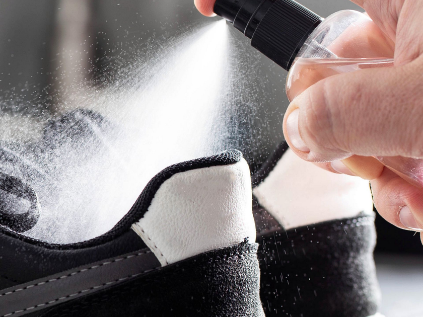 Vaporiser du nettoyant sur une basket noire et blanche avec un flacon pulvérisateur manuel
