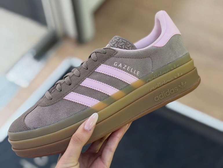 Baskets Adidas Gazelle grises et roses tenues à la main à l'intérieur