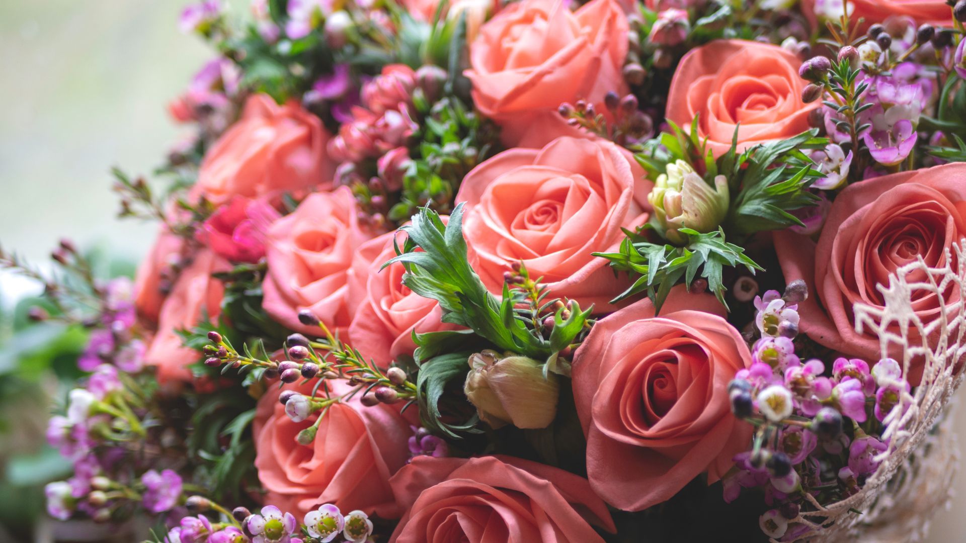 Eine Nahaufnahme eines Strausses aus rosa Rosen und lila Blumen