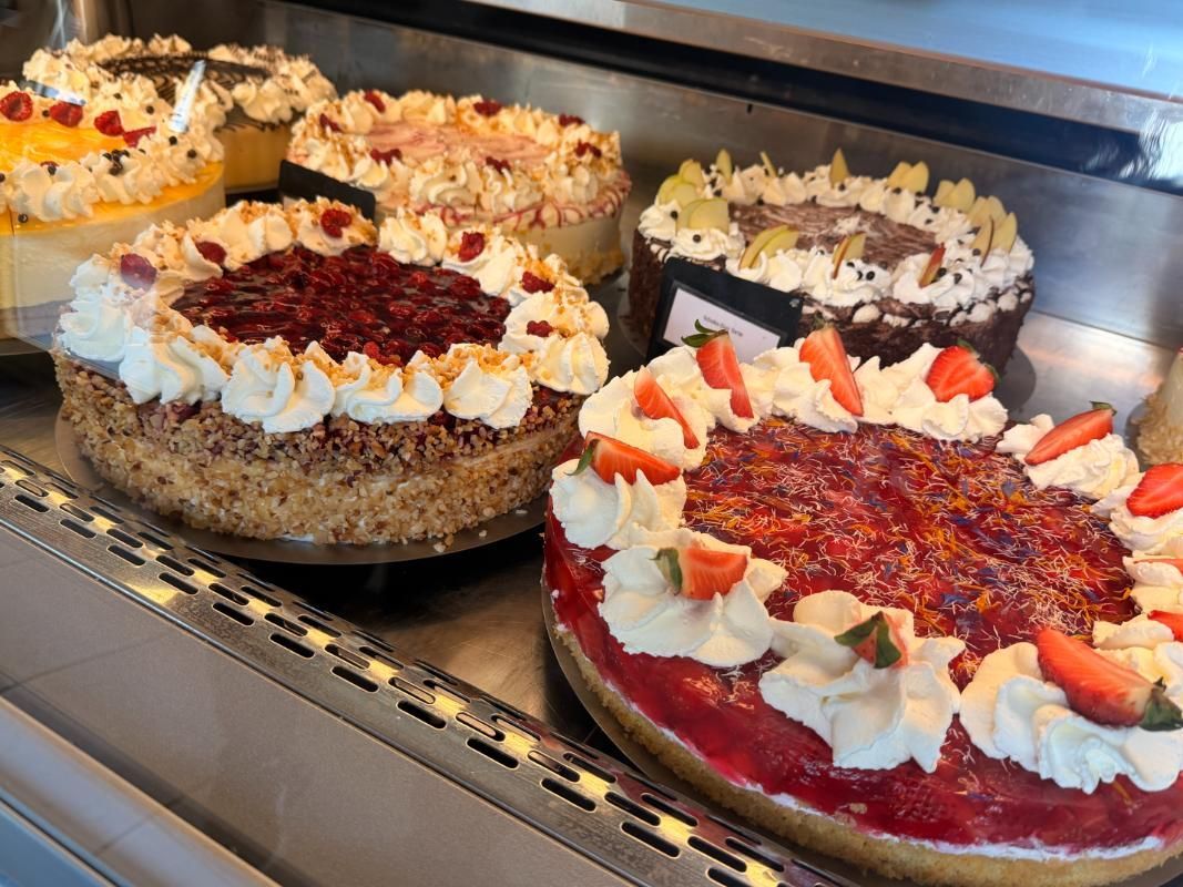 Auslage einer Bäckerei mit dekorierten Kuchen, verziert mit Früchten und Sahneglasur, auf einem Kühlregal