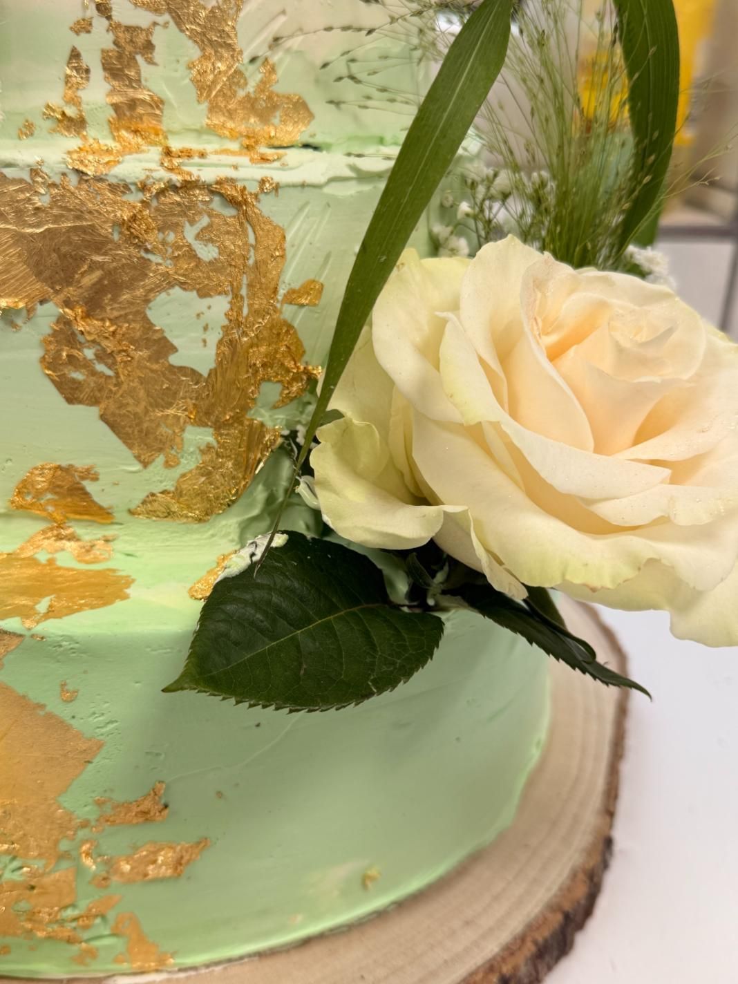Mintgrüner Kuchen mit Blattgold und weißer Rosenverzierung