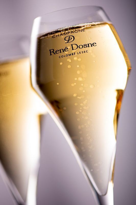 Gros plan sur une flûte à champagne René Dosne remplie de vin doré pétillant.