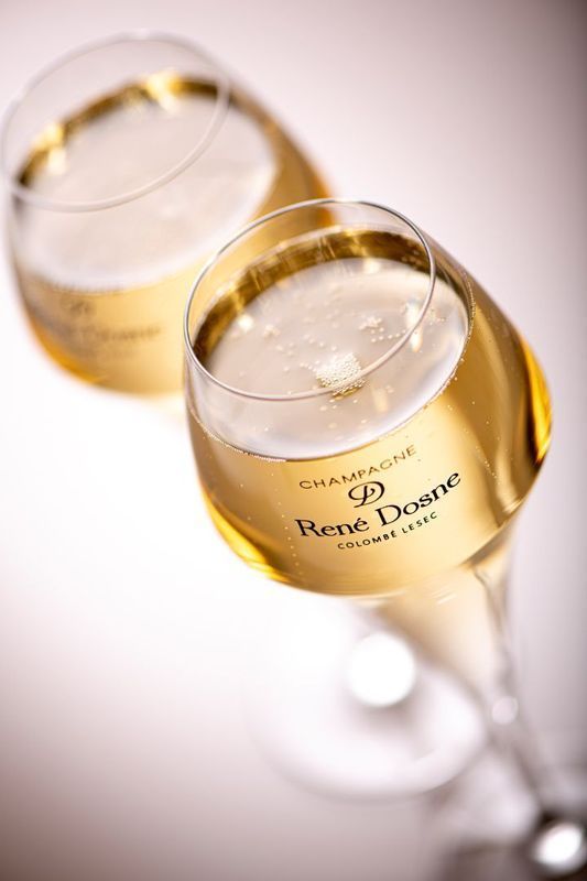 Deux flûtes à champagne remplies de vin mousseux, vues de dessus sur une surface blanche.