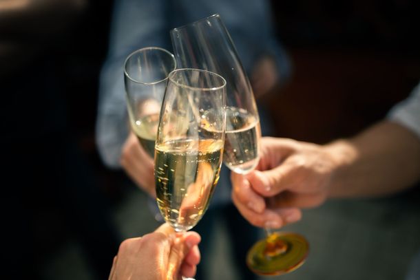 Des mains qui s'entrechoquent avec des flûtes de champagne lors d'un toast festif sur une table faiblement éclairée.