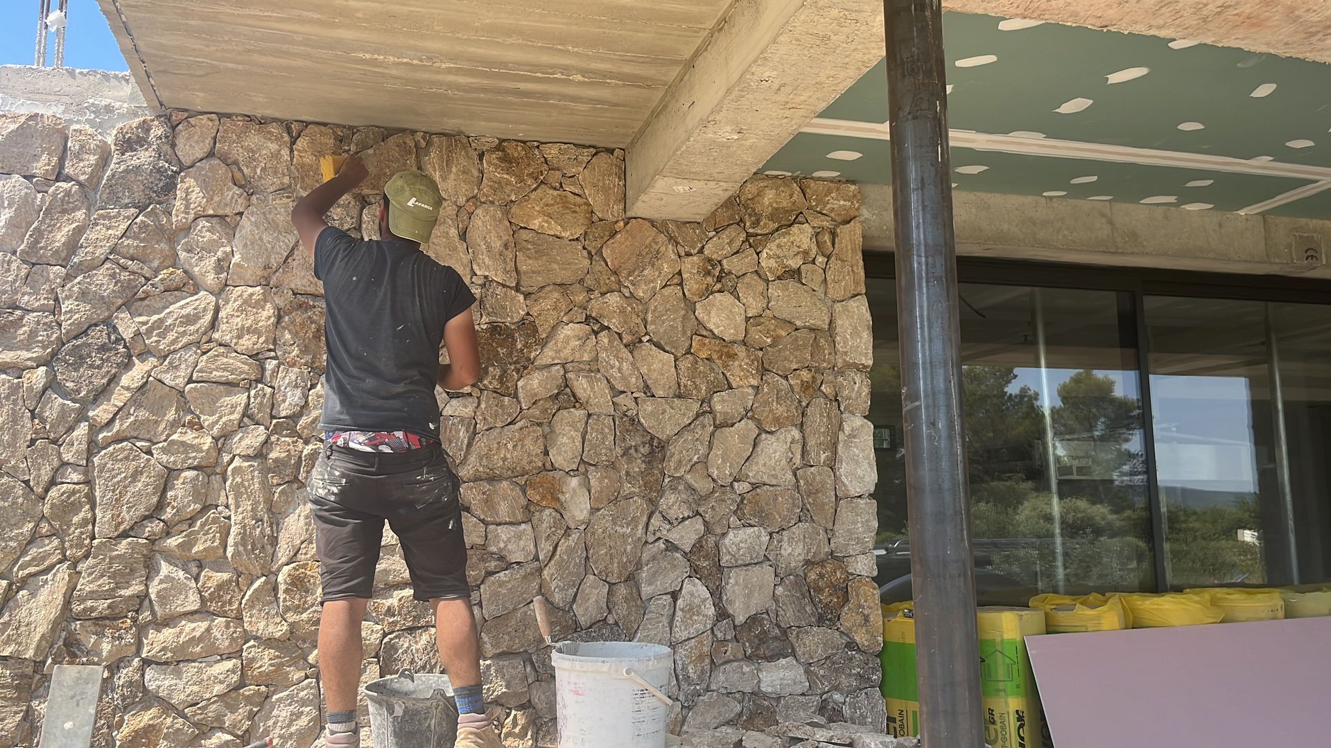 Personne appliquant du mortier sur un mur en pierre