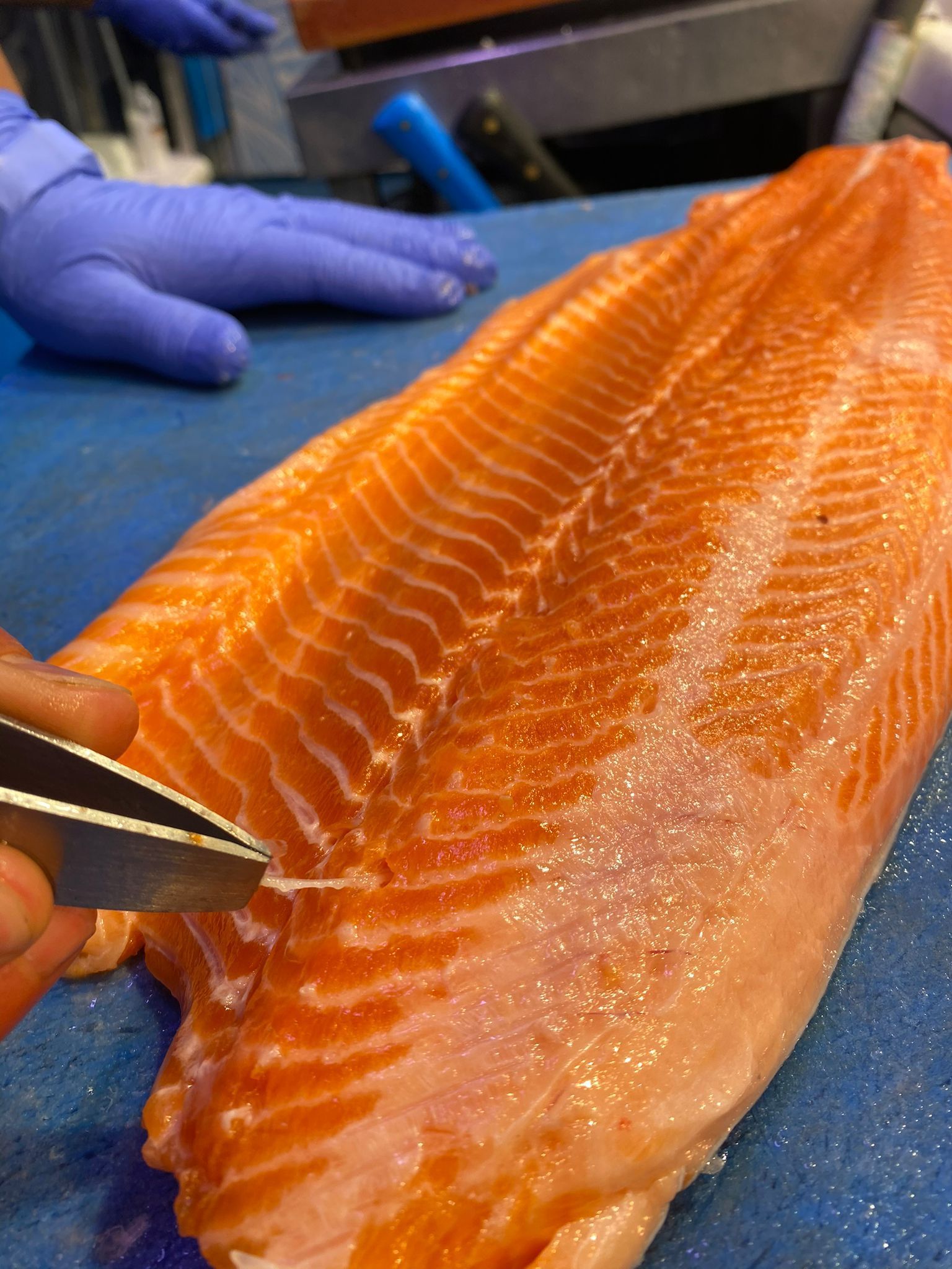 Una persona está cortando un trozo de salmón en una tabla de cortar.