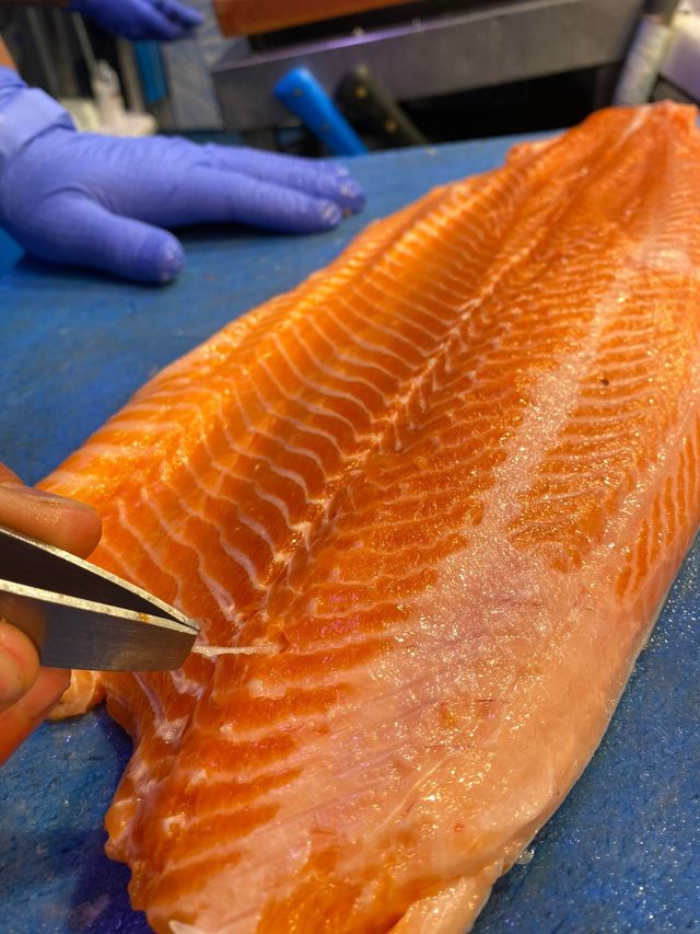 Una persona está cortando un trozo de salmón en una tabla de cortar.