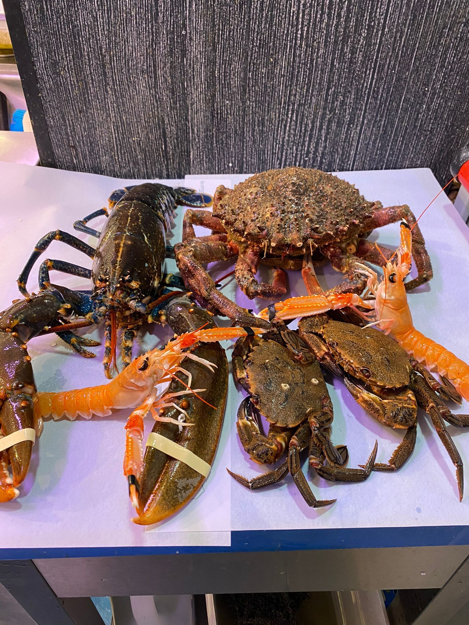 Un montón de cangrejos y langostas están sentados en una mesa.