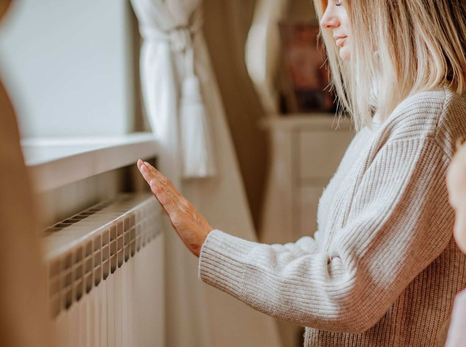Une femme blonde devant un radiateur