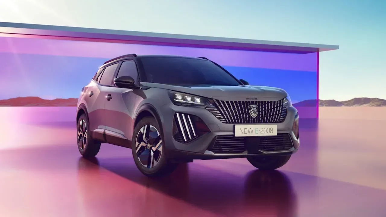 SUV plateado en una sala de exposición iluminada con luz púrpura, vista frontal en ángulo contra un fondo.