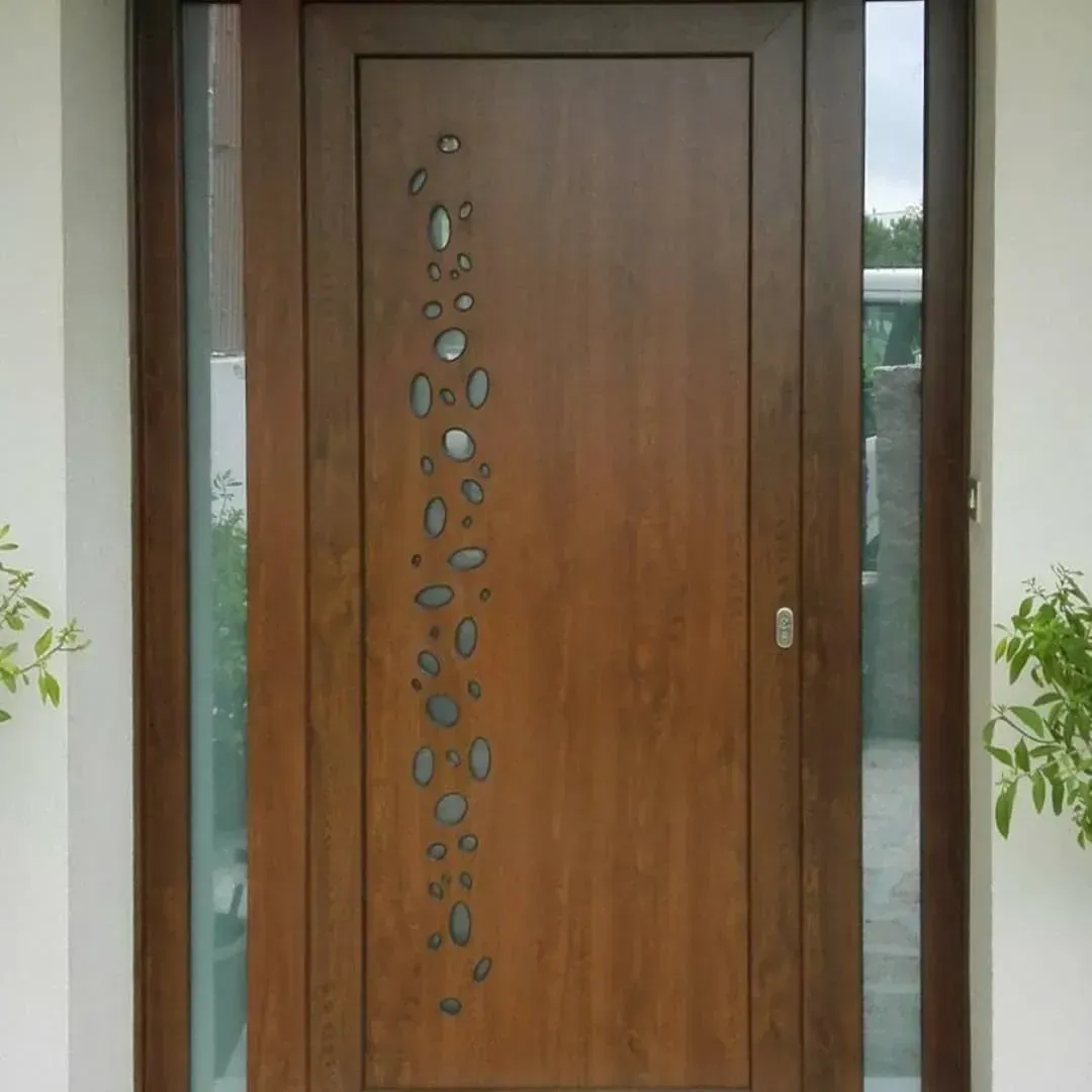 Puerta principal de madera con detalles de vidrio ovalados en vertical, flanqueada por plantas en macetas