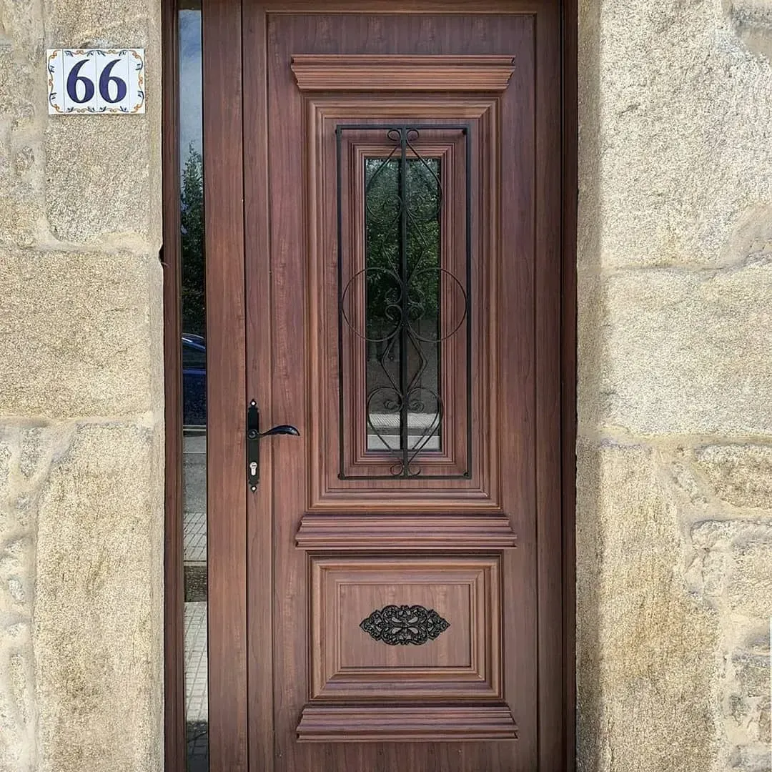 Puerta principal de madera con panel de vidrio y el número 66 en la fachada de piedra