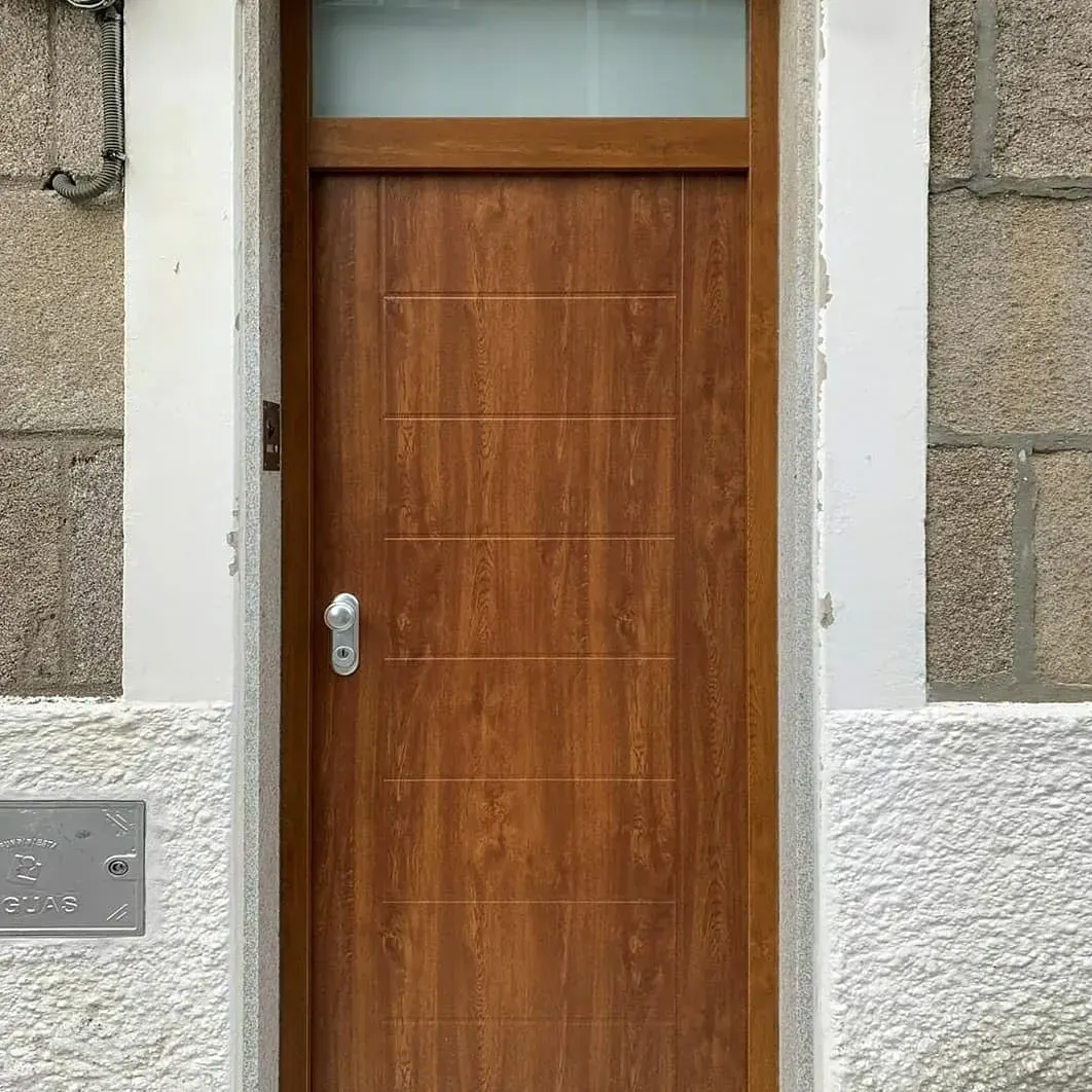 Entrada al TANATORIO con escalones cerrados por una verja, muros de piedra y árboles bajo un cielo despejado