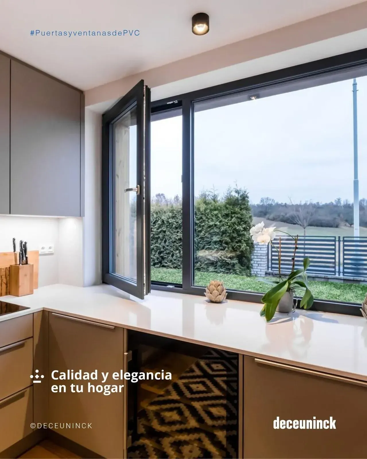 Ventana de cocina moderna y luminosa con marco negro abierto, encimera, plantas y vistas al jardín