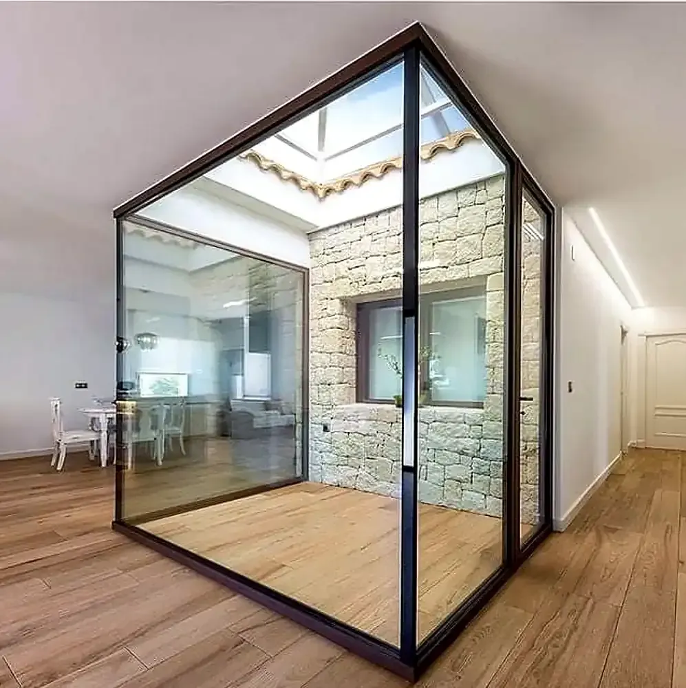 Habitación interior acristalada con suelo de madera, en una luminosa vivienda de estilo moderno