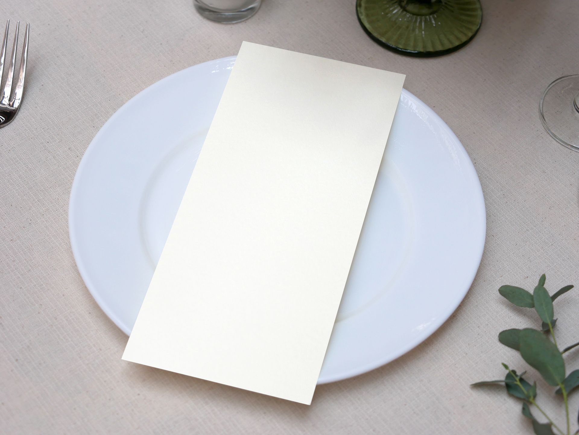 Une carte de menu blanche vierge repose sur une assiette blanche, posée sur une table, prête à recevoir des informations.