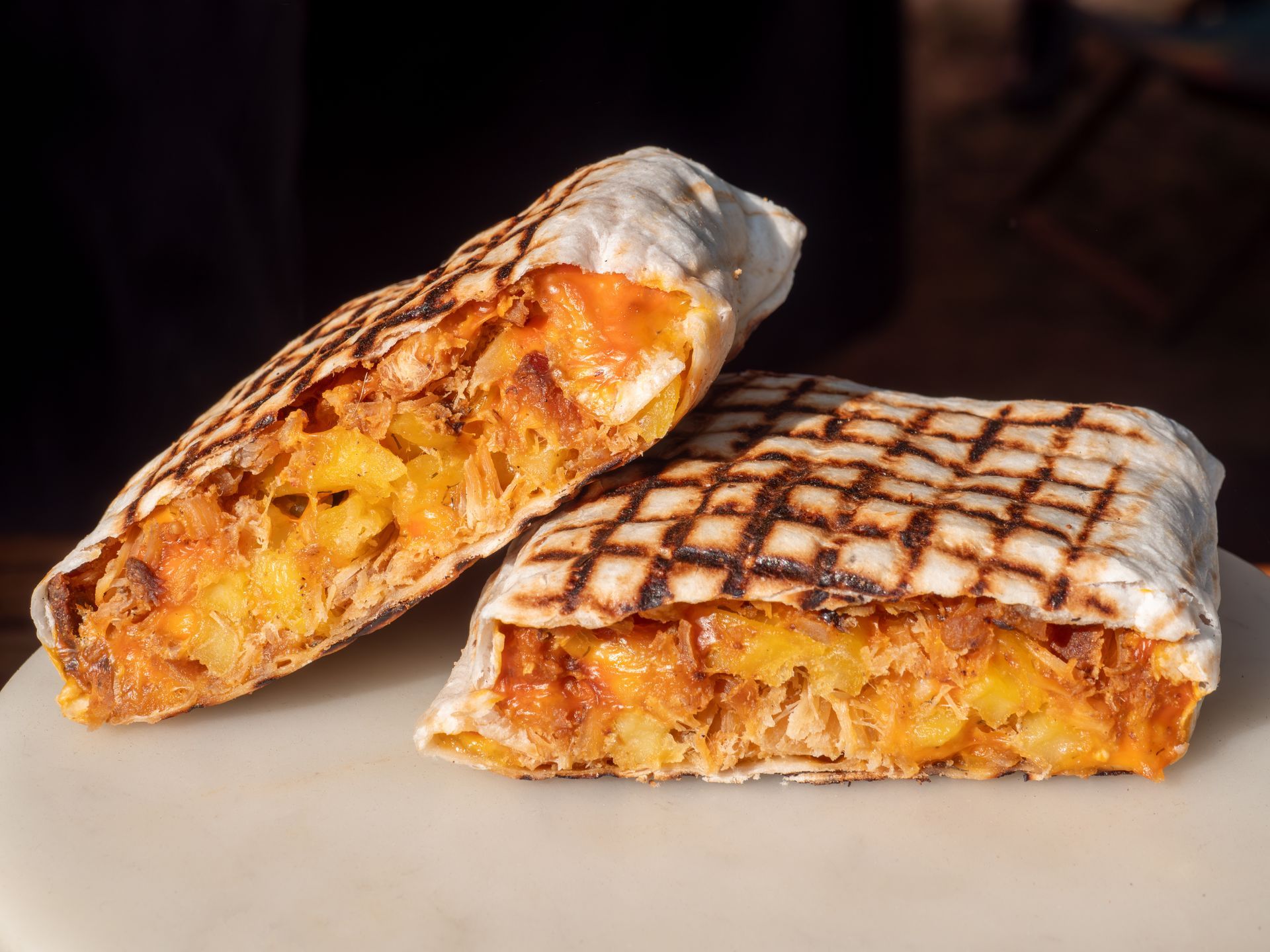 Sandwich plié et grillé, ouvert et garni. Wrap blanc avec marques de gril, garniture dorée.