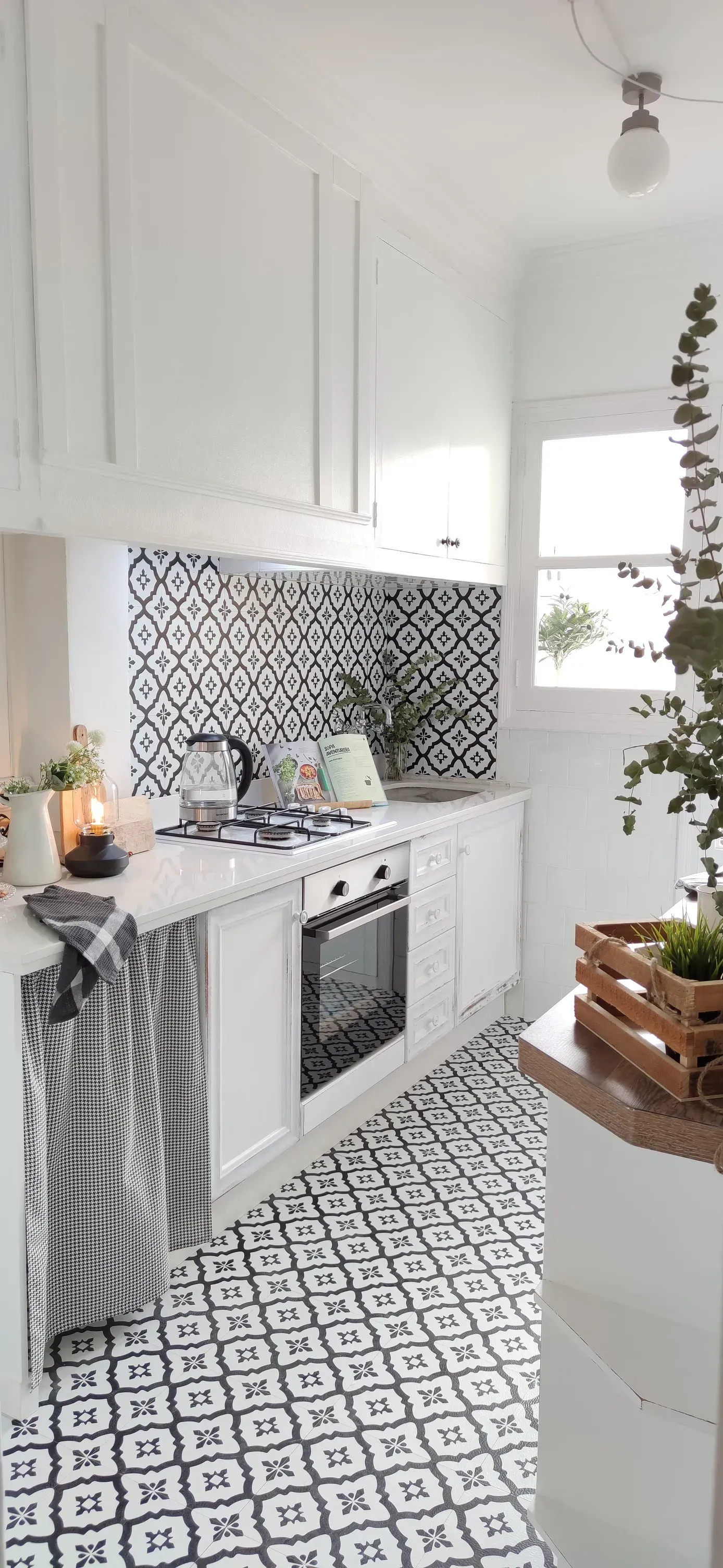 Una cocina con gabinetes blancos y piso de baldosas en blanco y negro.