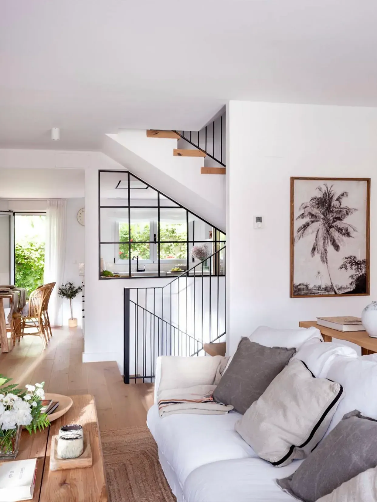 Una sala de estar con un sofá blanco y una imagen de una palmera en la pared.