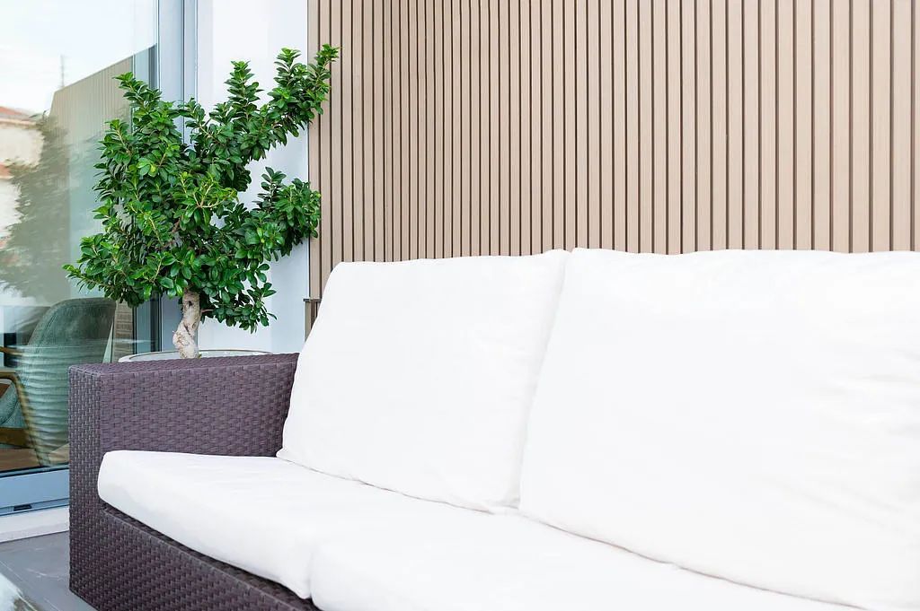 Una sala de estar con un sofá y una planta frente a una pared de madera.