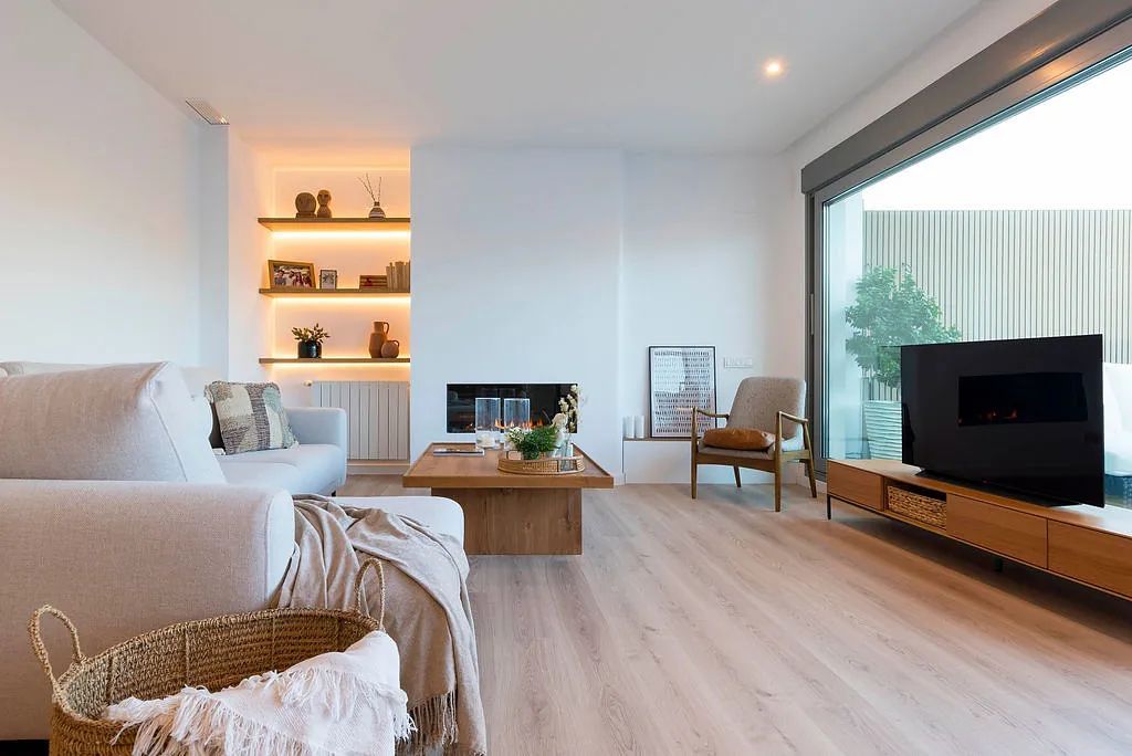 Una sala de estar con sofá, silla, mesa de café y televisión.