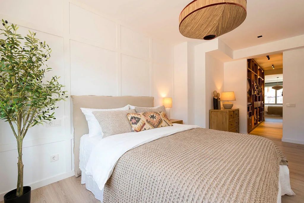 Un dormitorio con una cama grande y un árbol en la esquina.