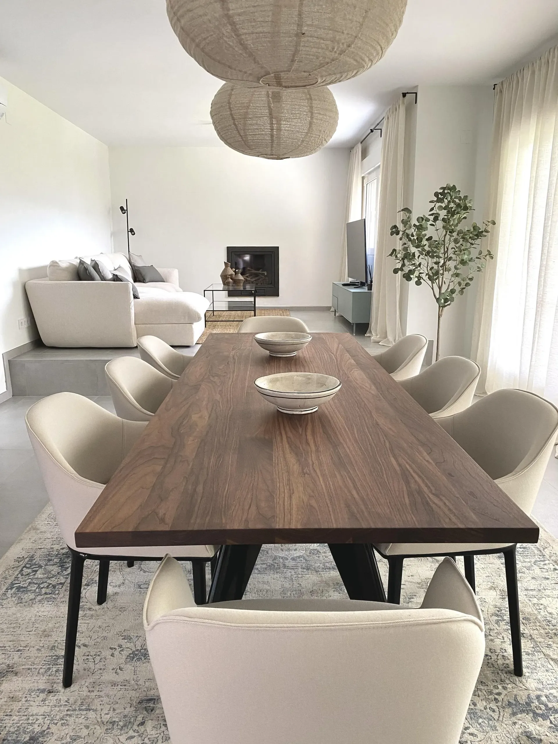 Una mesa de comedor larga de madera con sillas blancas en una sala de estar.