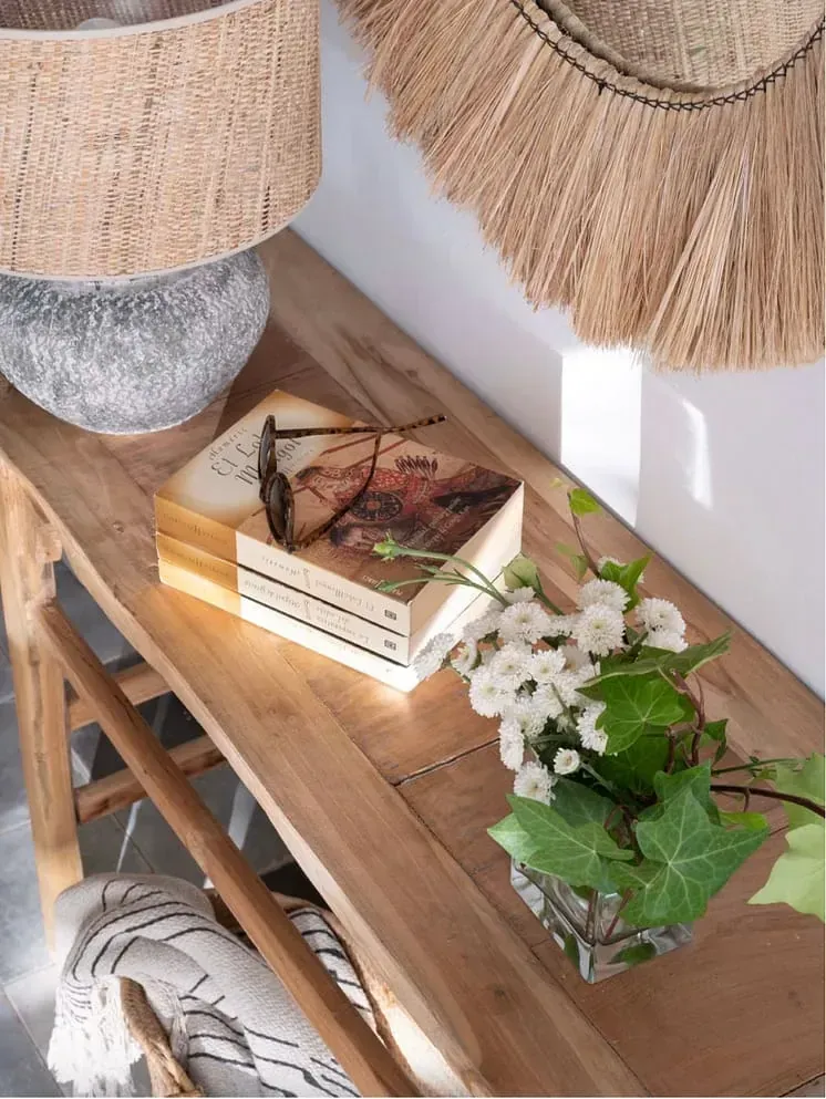 Una mesa de madera con un jarrón de flores y libros encima.