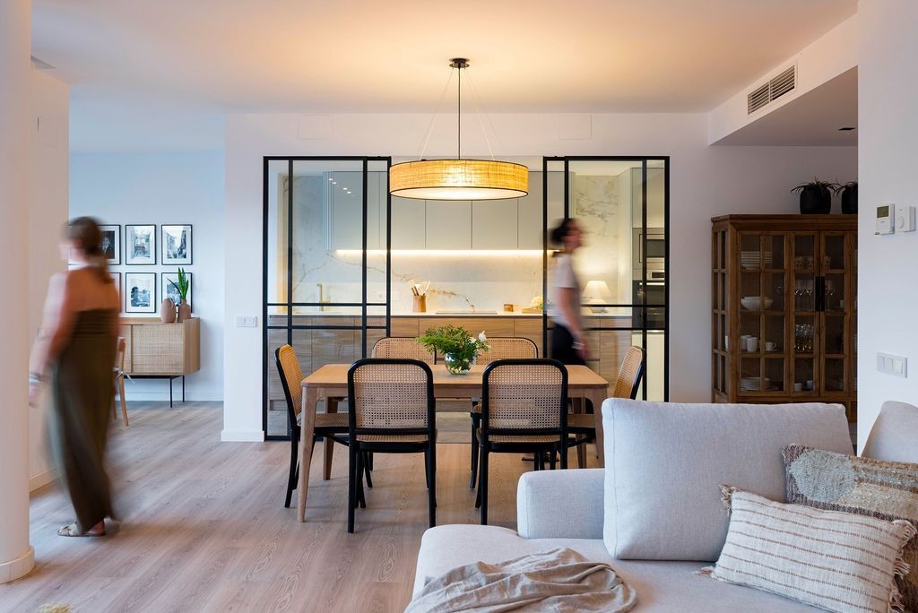 Una mujer entra a una sala de estar con una mesa de comedor y sillas.