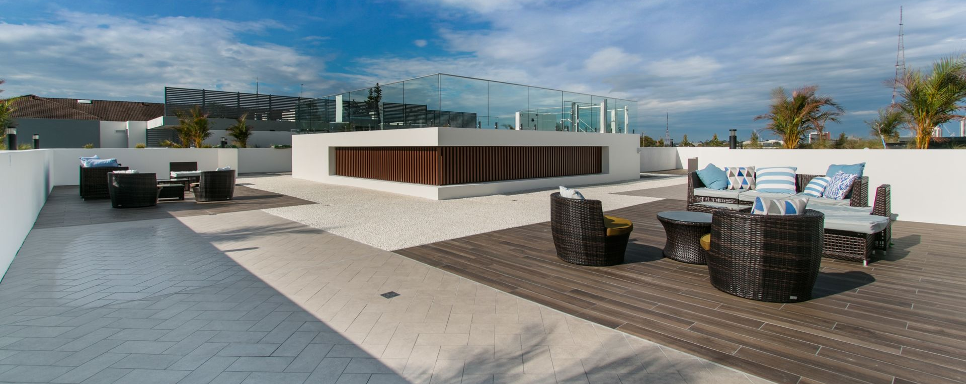 Terrasse sur le toit avec espaces de détente, bâtiment moderne aux accents de verre et de bois, ciel dégagé.