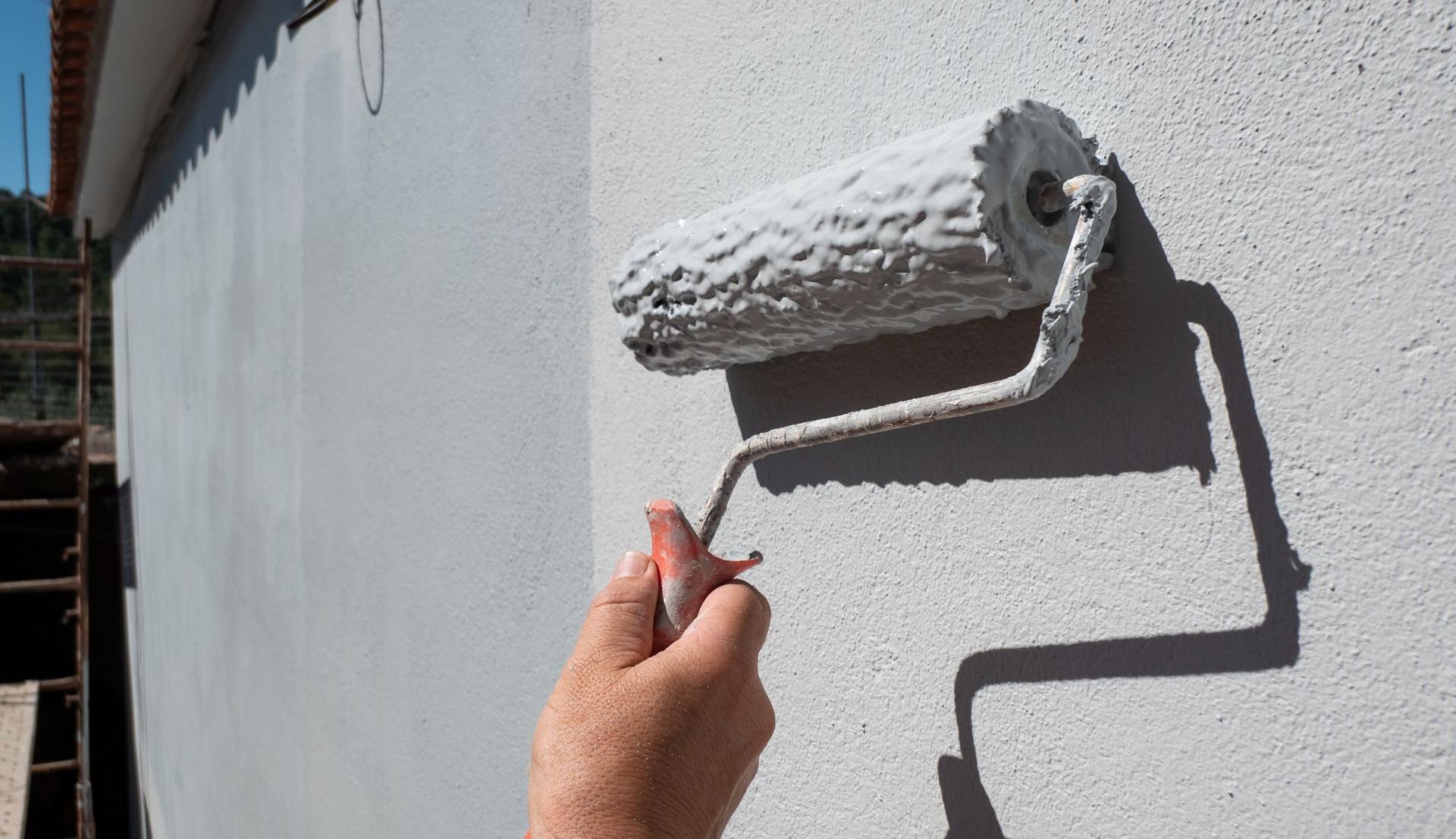 Une personne utilisant un rouleau à peinture sur un mur blanc.