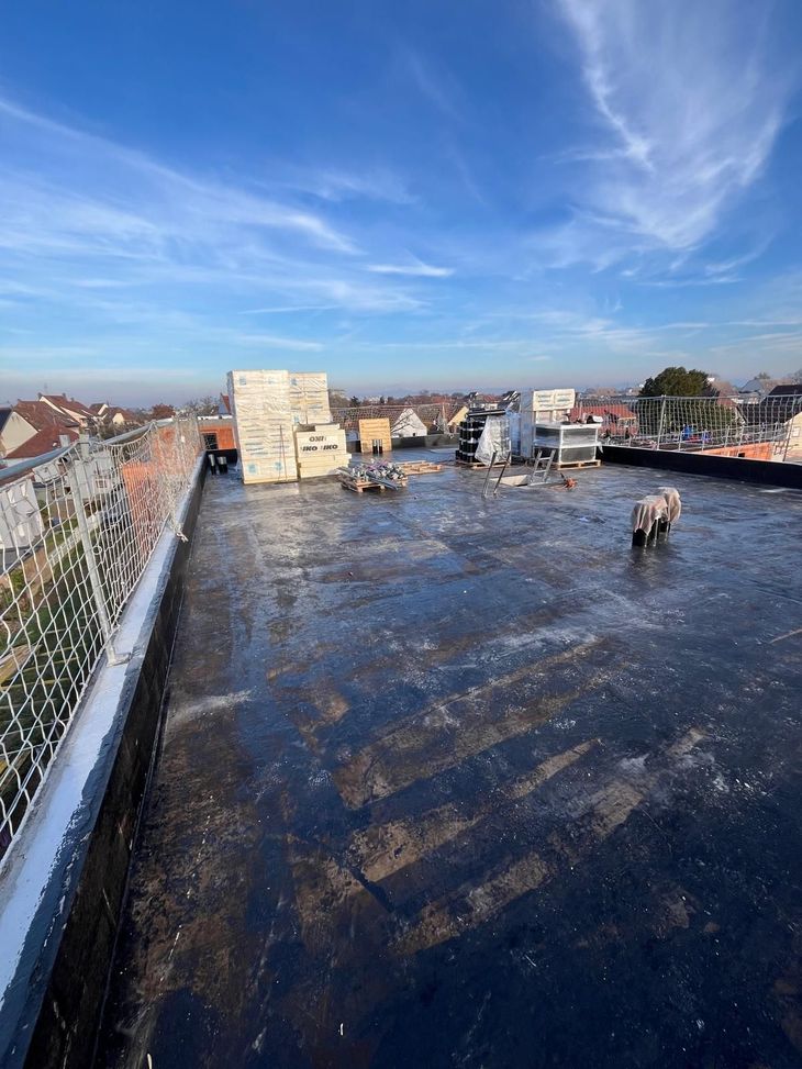 Toit jonché de débris, ciel bleu. Passages pour chiens gris. Filet de sécurité sur le côté.
